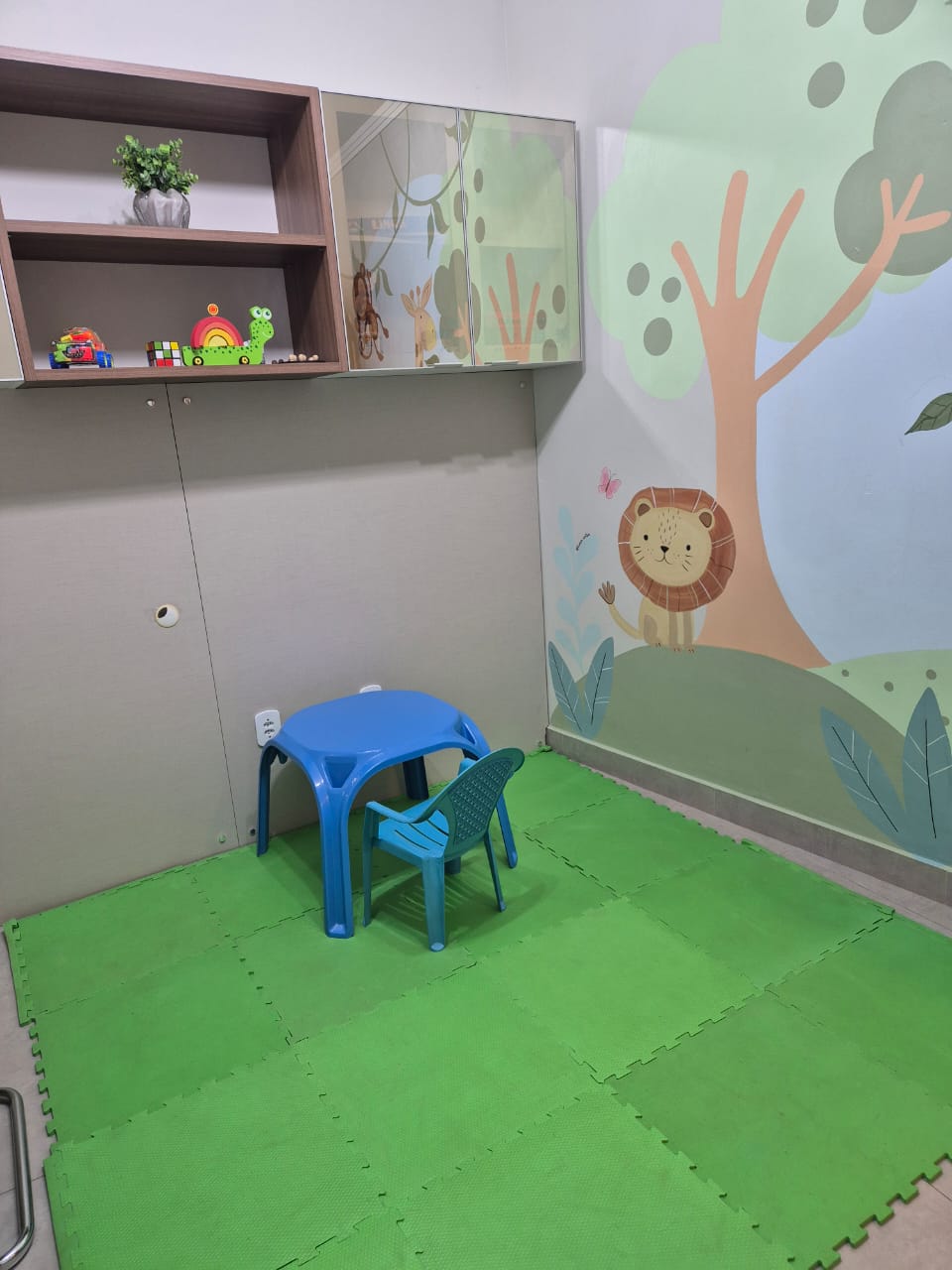 Sala infantil lúdica com painel de leão e mesa de atividades
